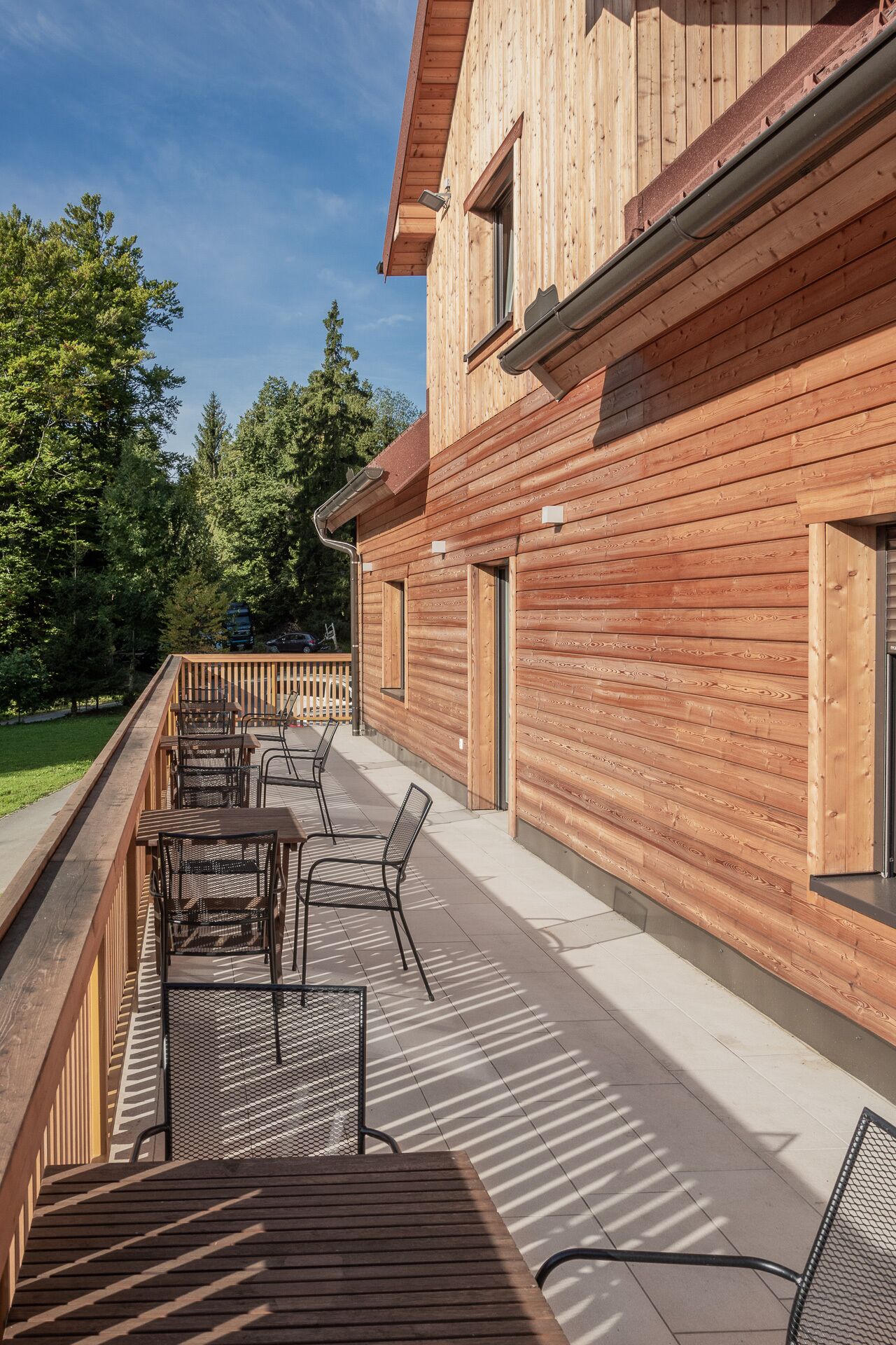 A wooden building with a deck area featuring outdoor seating.