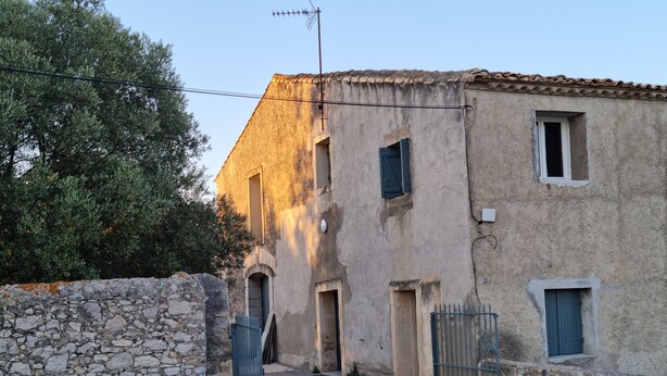 Un edificio rústico con pared de piedra, varias puertas y una reja de metal.