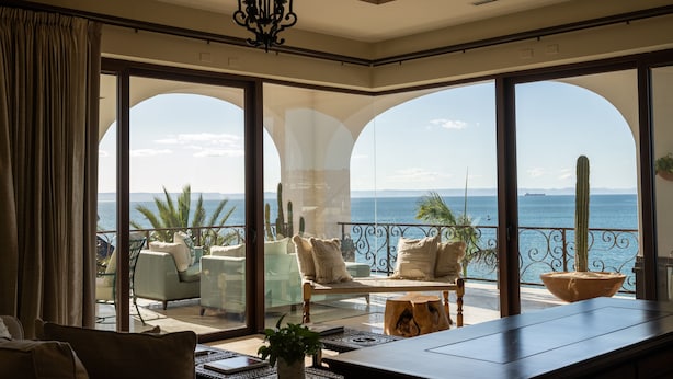 A spacious balcony with a view of the sea, furnished with a sofa, chairs, and a dining table.