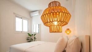 Een slaapkamer met een bed, een hanglamp en een raam.