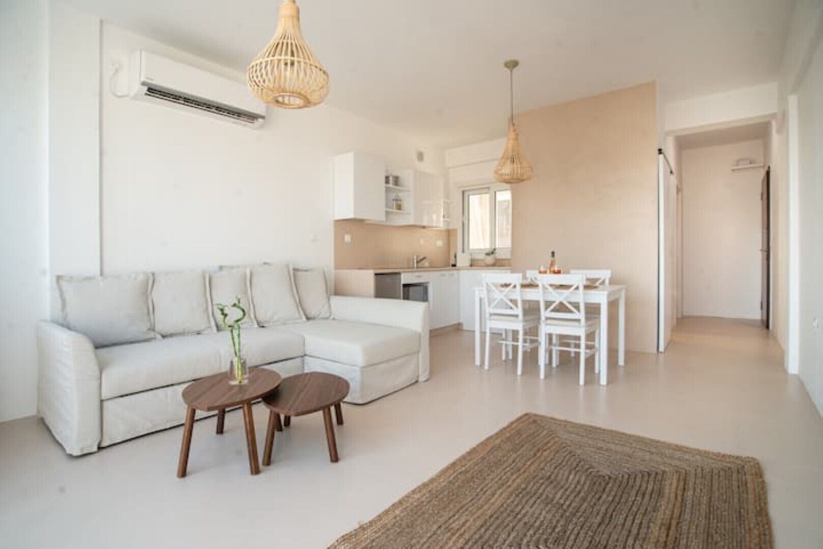 A modern living room with a sofa, two wooden side tables, and a dining area with a table and chairs.