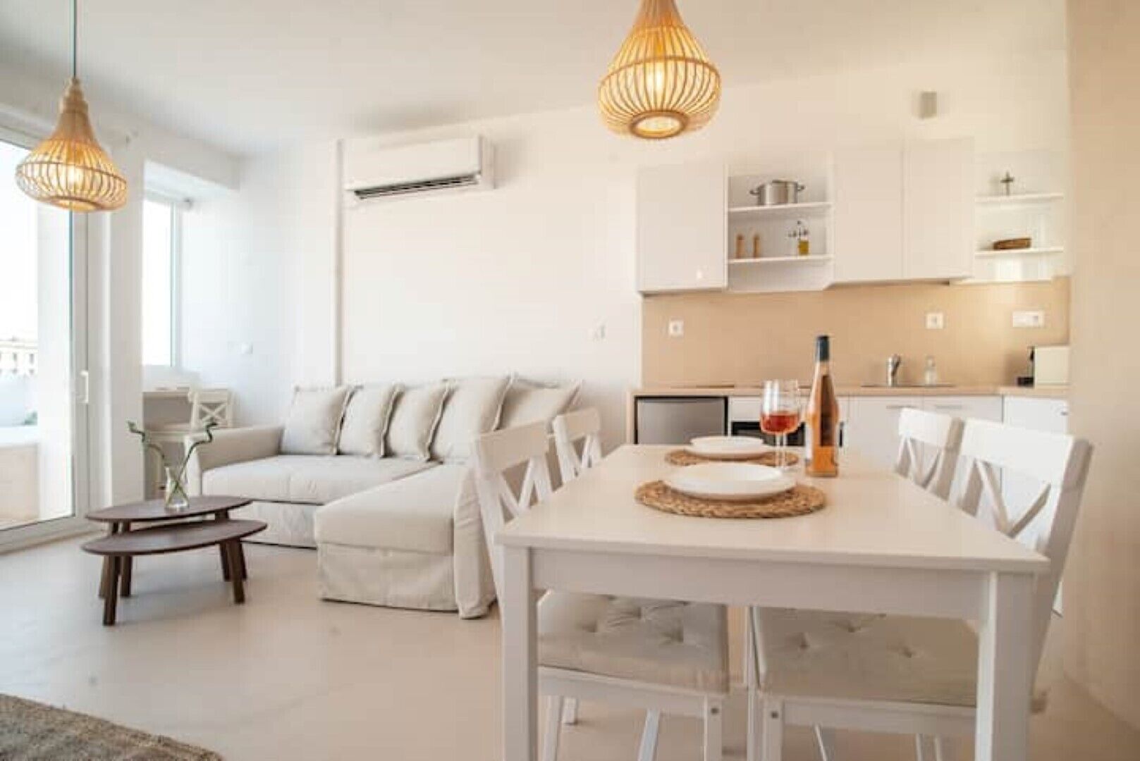 A modern living room with a white sofa, a dining table with chairs, and pendant lights.