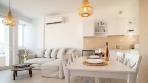 Een moderne woonkamer met een witte bank, een eettafel met stoelen en hanglampen.