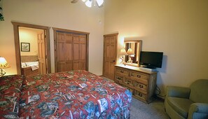 Un dormitorio con cama, cómoda, televisor y una silla.