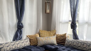 A corner seating area with a cushioned bench, a wooden frame, and a window with curtains.