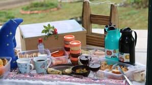 Een picknickopstelling met verpakkingen eten, drinken en een fles wijn op een tafel.