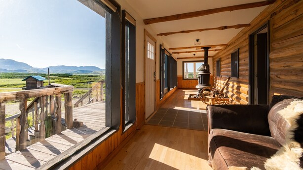 Una baita di legno con veranda e vista sulle montagne.