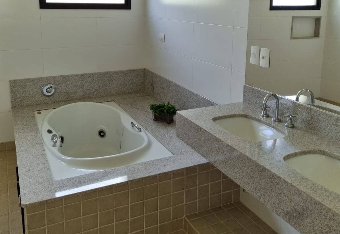 Un baño con una bañera grande, dos lavamanos y una pequeña planta en maceta.
