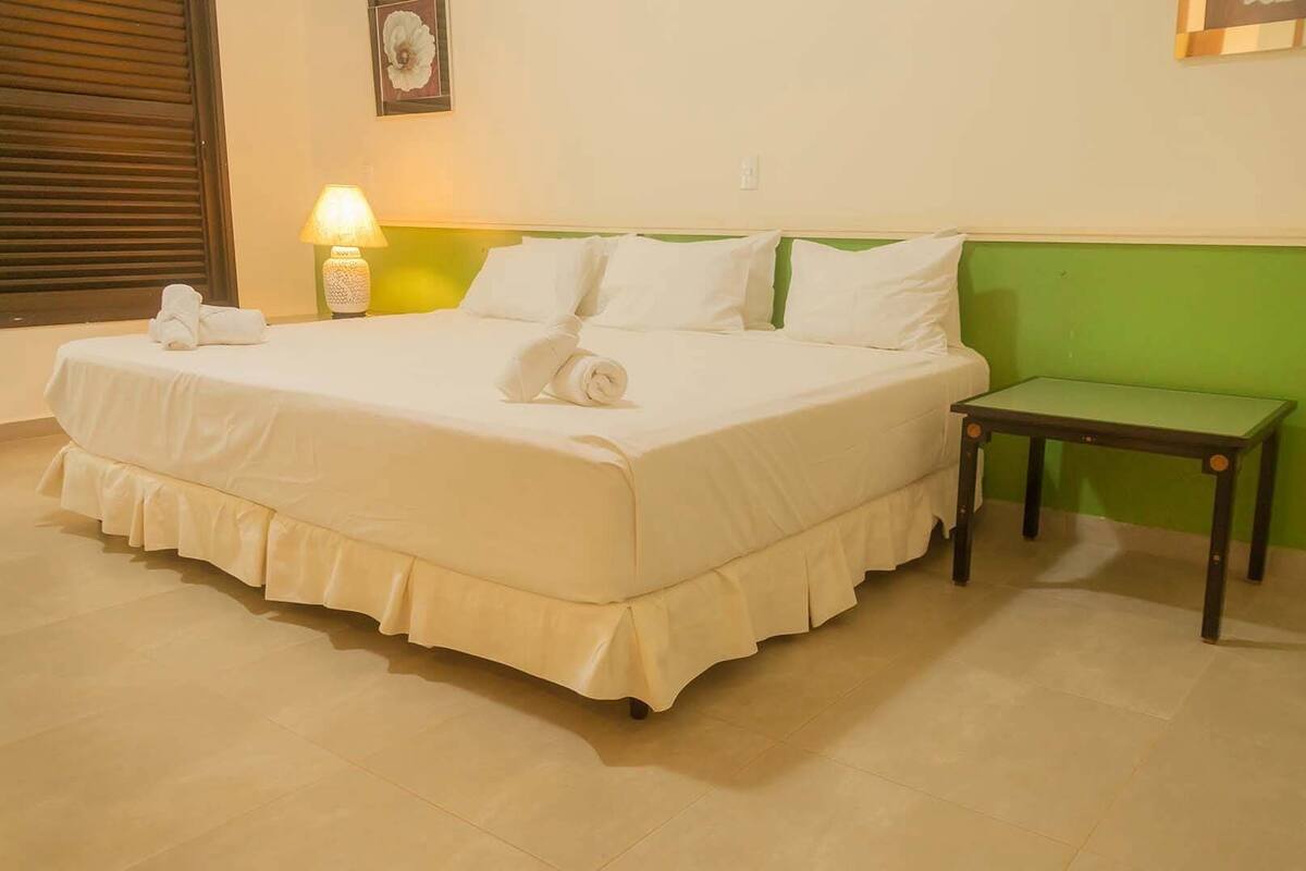 Une chambre d’hôtel avec un grand lit, une table de chevet et un mur d’accent de couleur verte.