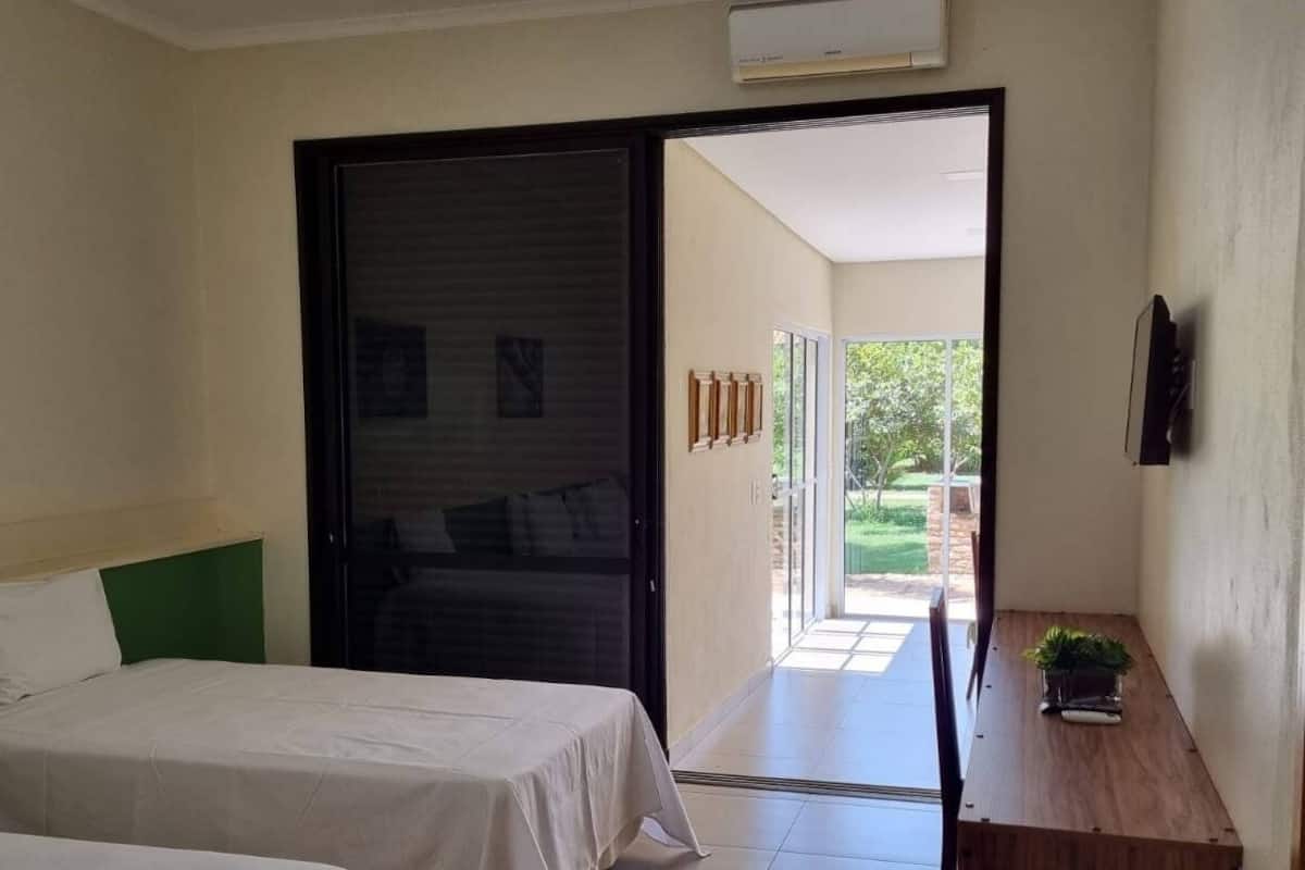 Une chambre d’hôtel avec un lit, une petite table sur laquelle est posée une plante, et une porte coulissante donnant sur un balcon.