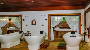 A spa room with two large tubs, a small table with a plant, and a window with curtains. - Botânico Hotel Fazenda e SPA (Aracatuba)
