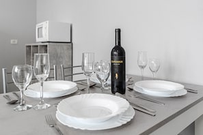 Ein Esstisch ist gedeckt mit weißen Tellern, Weingläsern und Besteck, dazu eine Flasche Canarius Wein.