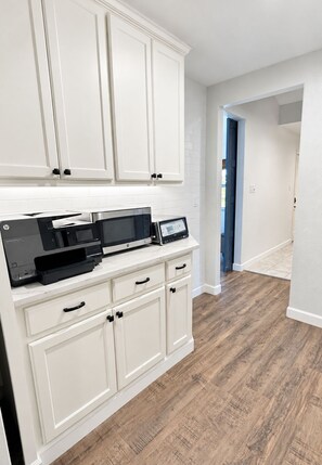 A kitchen with white cabinetry, a countertop with HP printers, and a wooden floor. - Relocation? Insurance Claim? Rehab? Best LOCATION in Flower Mound (Flower Mound)
