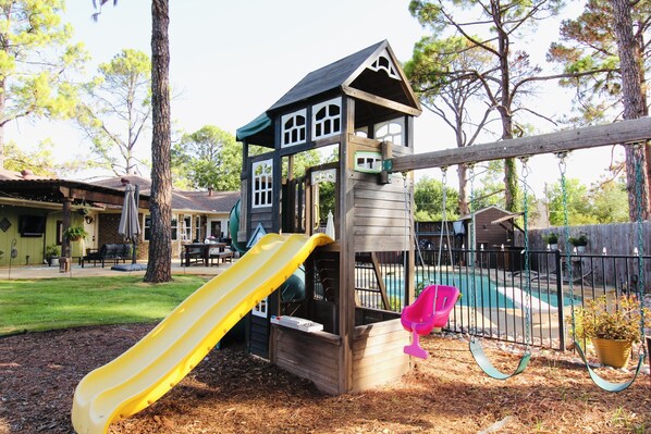 A playground with a slide and a swing set.