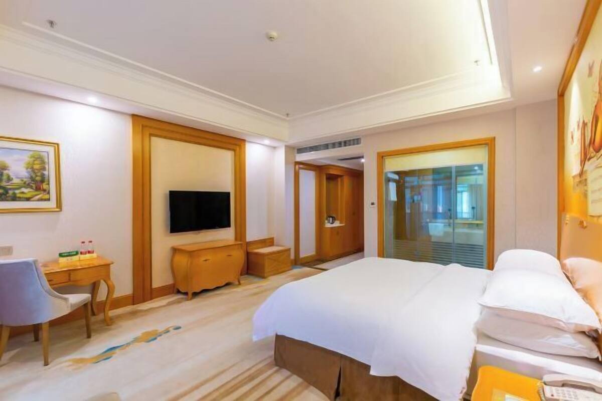 A hotel room with a bed, a TV, a desk, and a chair.