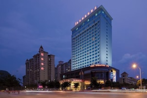 Hotel de vários andares com localização de destaque na esquina, com grande placa e janelas iluminadas.