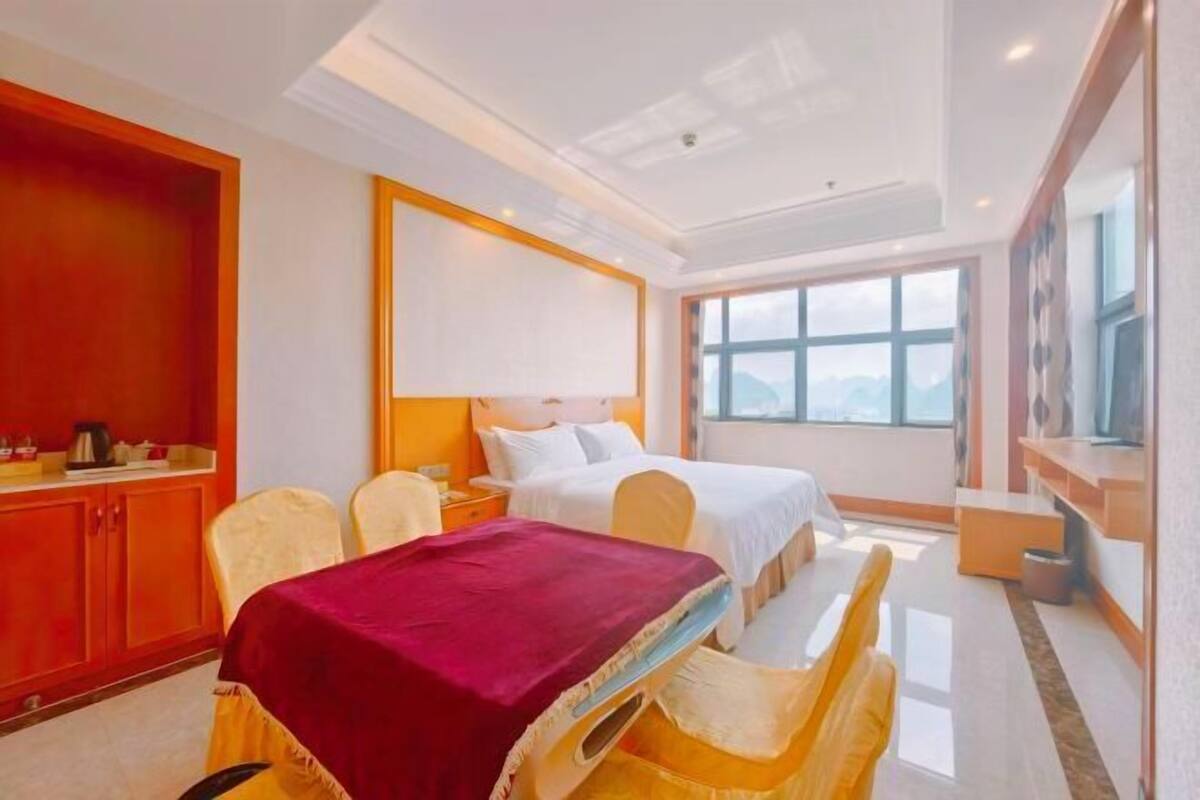 A hotel room with a bed, a desk, a chair, a TV, and a window.
