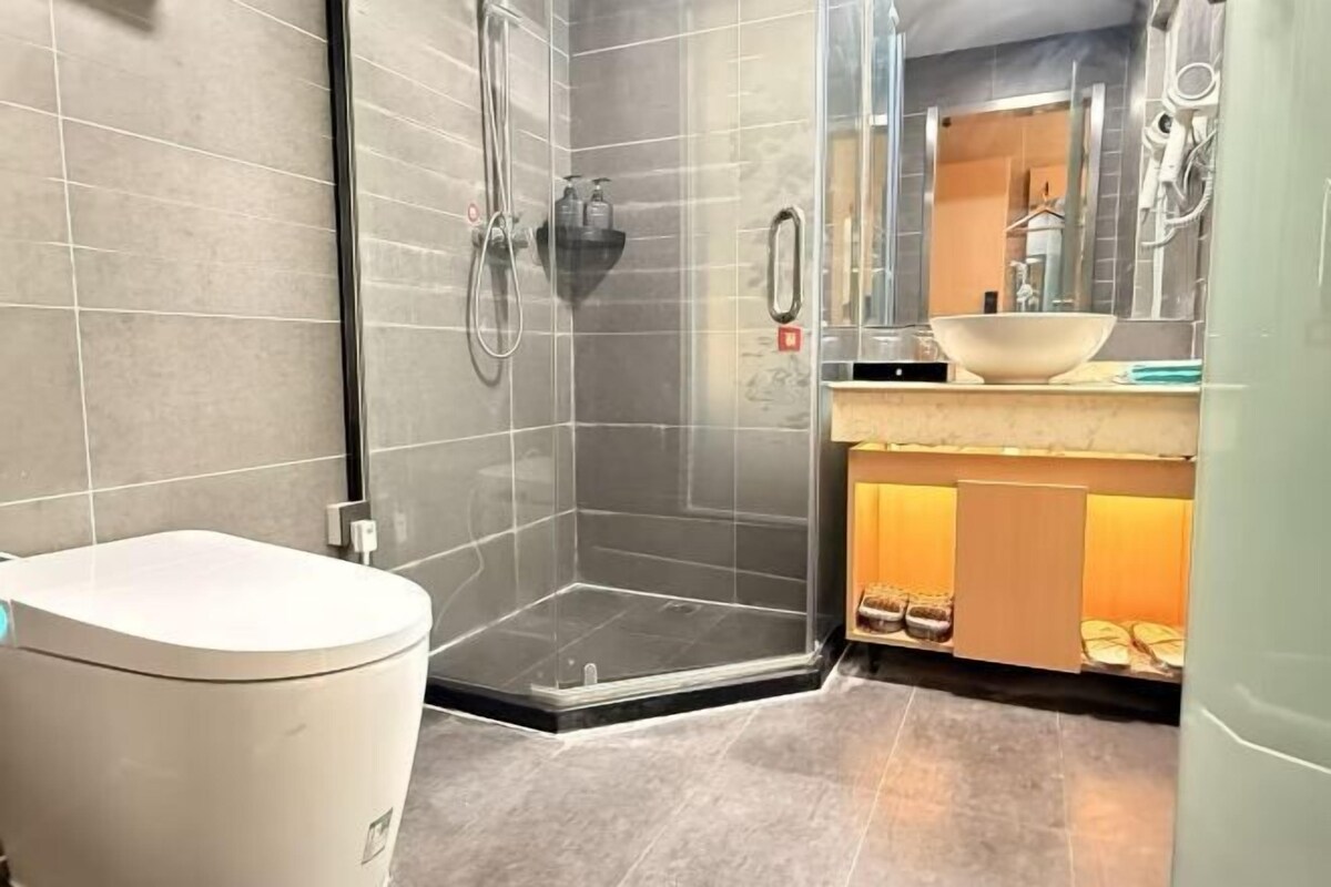 Un baño moderno con inodoro, ducha envuelta en vidrio, lavabo y espejo.
