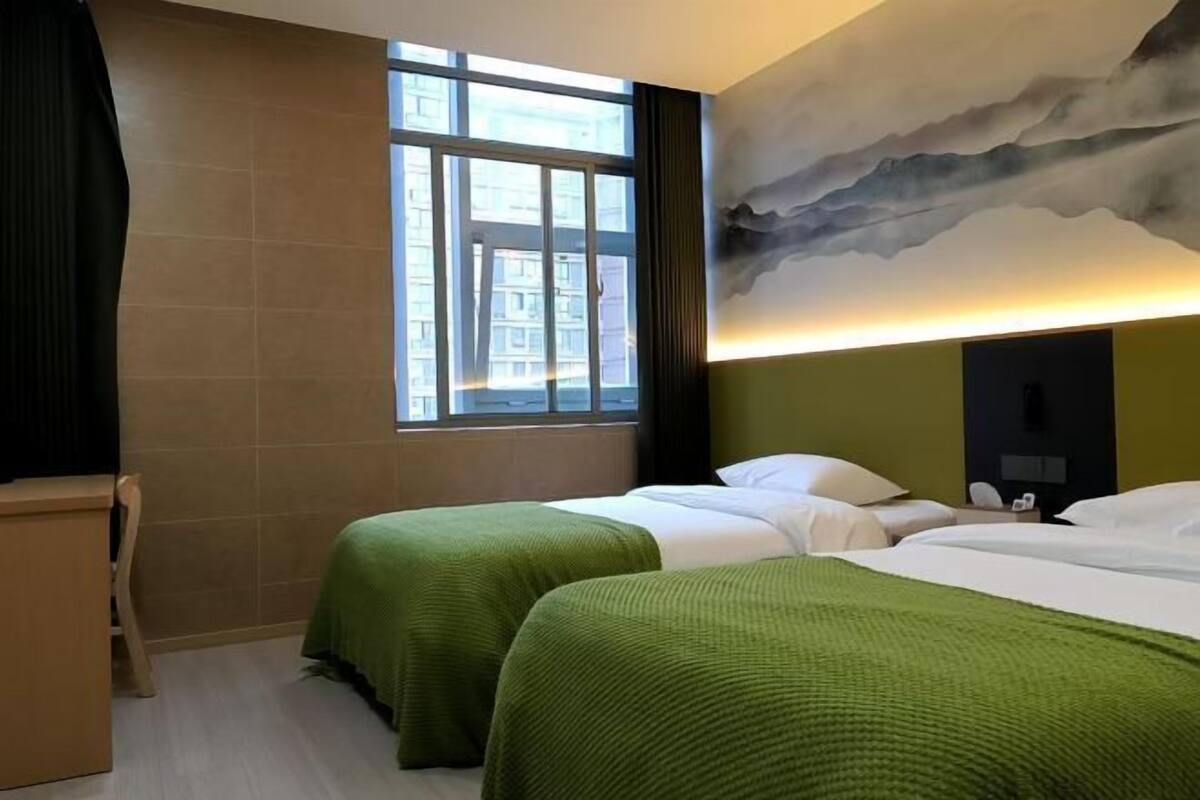 A hotel room with two beds, a large window, a painting on the wall, and a desk.
