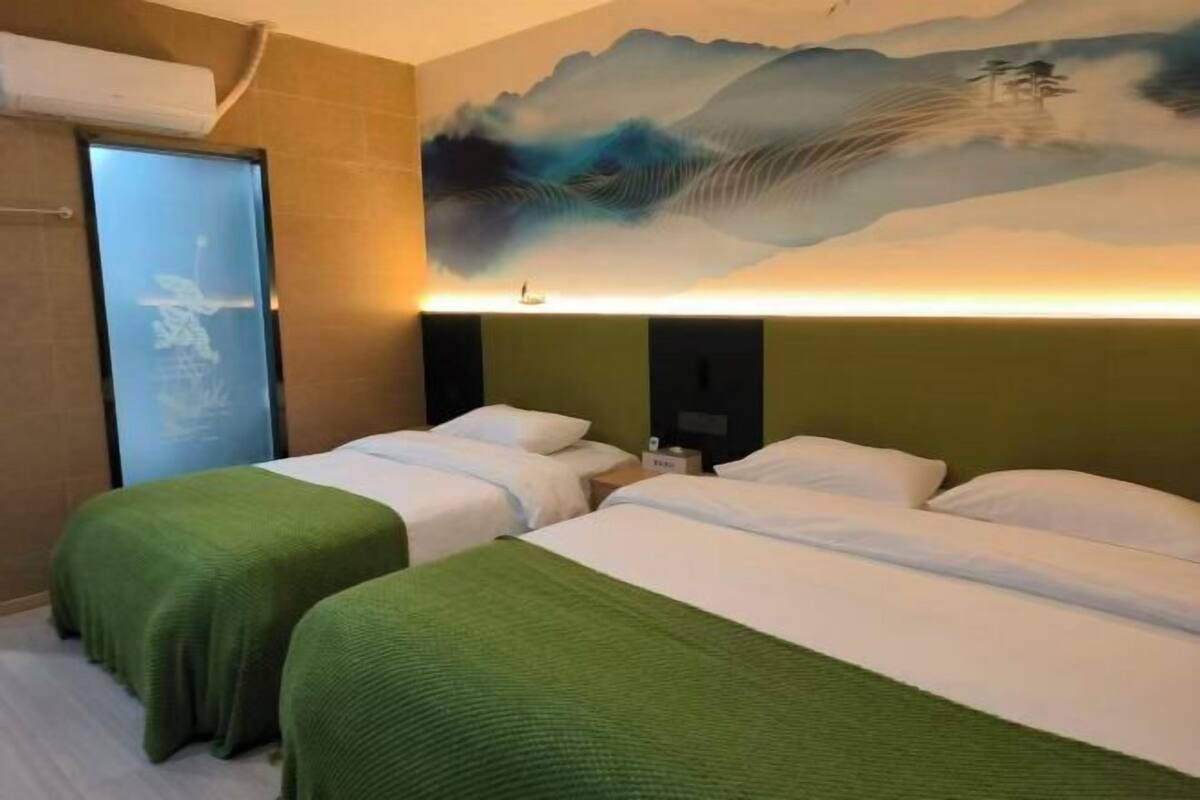 A hotel room with two beds, a large painting on the wall, and a window with a view.