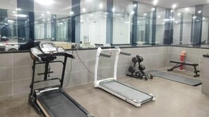 Une salle de sport équipée de tapis de course, d’haltères et d’un banc de musculation.