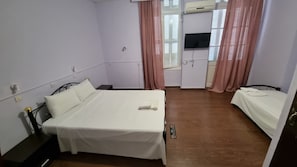 A small, clean room with a single bed, a bedside table, a desk, and a TV. - Hotel Feron (Athens)