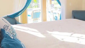 Ein Schlafzimmer mit Bett, Vorhängen und Blick auf einen Außenbereich.