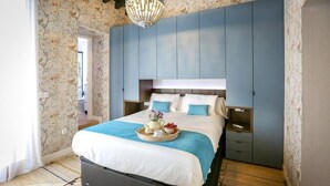 Une chambre avec un grand lit, une commode et une table de chevet. Un lustre est suspendu au-dessus du lit.
