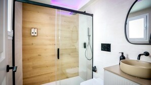 Une salle de bain moderne avec une douche à parois de verre, des toilettes blanches et un lavabo beige avec un miroir au-dessus.