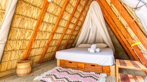 Une pièce triangulaire et chaleureuse, dotée d’un toit de chaume, d’un lit à baldaquin et d’un panier tressé.