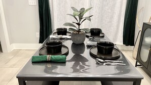 A dining table set with black bowls, plates, and cutlery, a green napkin, and a potted plant. - Modern & Bright Townhouse 26th Ave (Nashville)