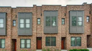 A row of modern brick buildings with large windows and doors, a paved parking area, and small plants in front. - Modern & Bright Townhouse 26th Ave (Nashville)