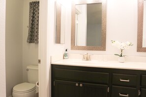 A bathroom with a toilet, a sink with a mirror, and a cabinet.