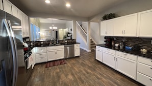 Una cocina moderna con armarios blancos, electrodomésticos de acero inoxidable y suelo de madera.