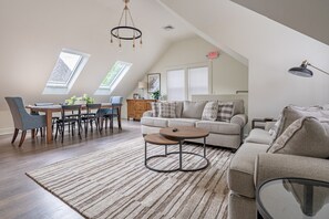 A spacious loft apartment with a dining area, a sofa, and a coffee table. - 51 Church Street, Lenox MA - One Bedroom Unit (Lenox)