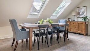Ein Essbereich mit Holztisch und Stühlen, einer Pflanze auf dem Tisch und einer Kommode mit Schubladen.