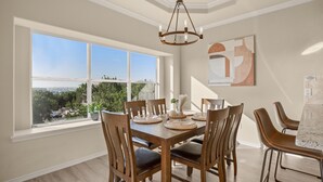 Une salle à manger dotée d’une grande fenêtre, d’un lustre et d’une table dressée pour six personnes.