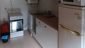 A compact kitchen with white cabinets, a built-in oven, a microwave, and a sink. - The Corner of Azarrulla (Azarrulla)