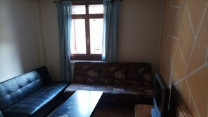 A living room with a sofa, a coffee table, and a TV stand. - The Corner of Azarrulla (Azarrulla)