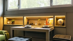 A modern kitchen with a dining table, shelves with kitchenware, a globe, and a green armchair. - Loft on 1236 129A (Ortisei)