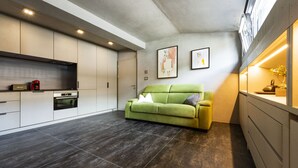 A modern kitchen with built-in appliances, a green sofa, and a small yellow chair. - Loft on 1236 129A (Ortisei)