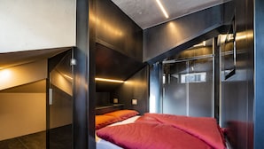 A modern, compact bedroom with a bed, a small seating area, and a window. - Loft on 1236 129A (Ortisei)