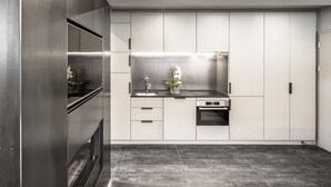 A modern kitchen with stainless steel appliances, white cabinetry, and a tiled floor. - Loft on 1236 129A (Ortisei)