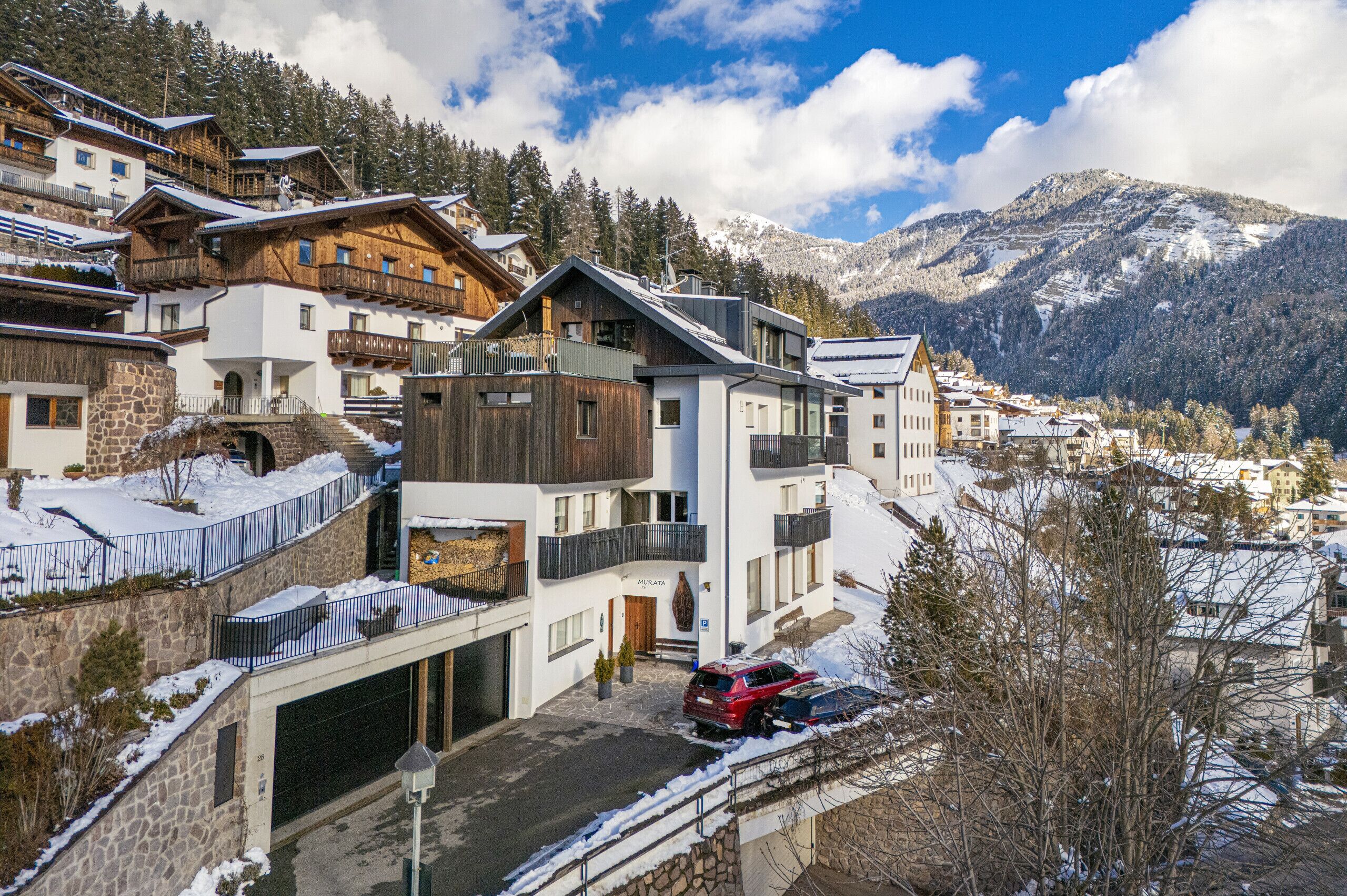 A modern hotel with multiple floors, balconies, and a view of snow-covered mountains.