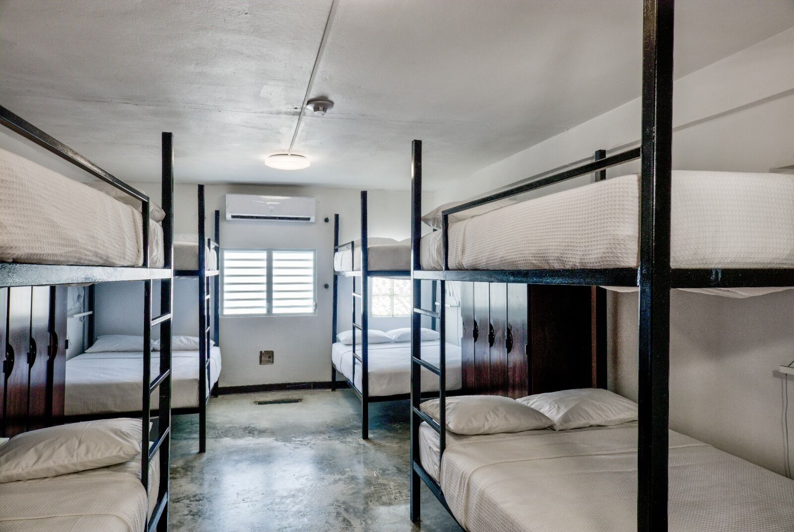 Um dormitório com beliches, ventilador de teto e janela com cortinas.