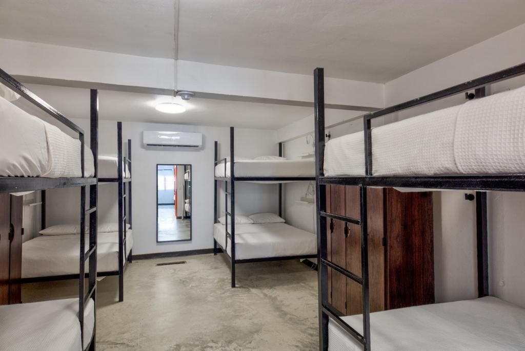 Une chambre de dortoir avec des lits superposés, une porte et un appareil de climatisation.