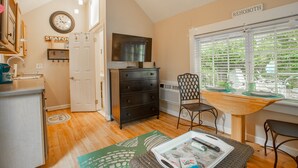 A cozy kitchen with a dining area, a TV, and a window with blinds. - Rehoboth Beach Efficiency Downtown Deck Sleeps 2 (Rehoboth Beach)