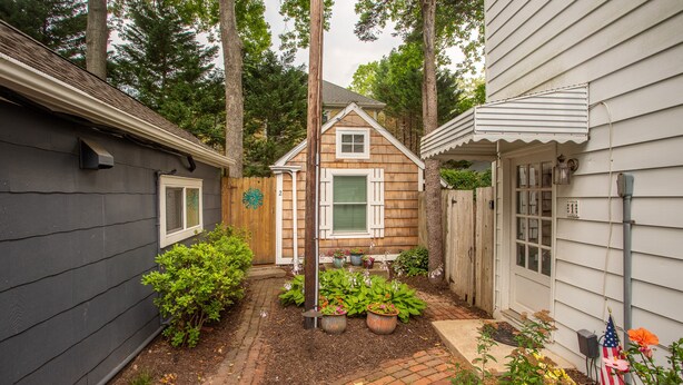 A small wooden house with a brick pathway, surrounded by greenery and potted plants. - Rehoboth Beach Efficiency Downtown Deck Sleeps 2 (Rehoboth Beach)