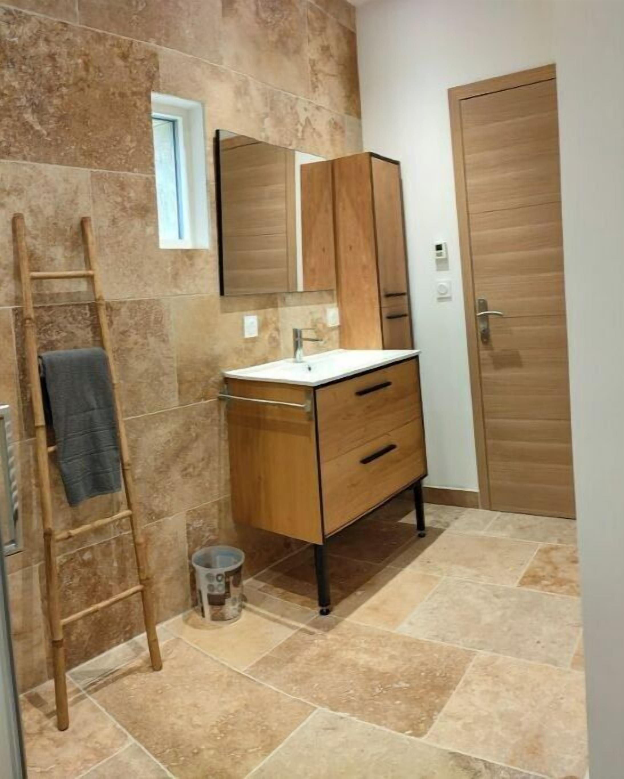A bathroom with a wooden vanity, a mirror, and a tiled floor.