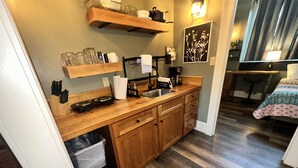 Una cocina compacta con muebles de madera, un lavamanos y una encimera con varios objetos.